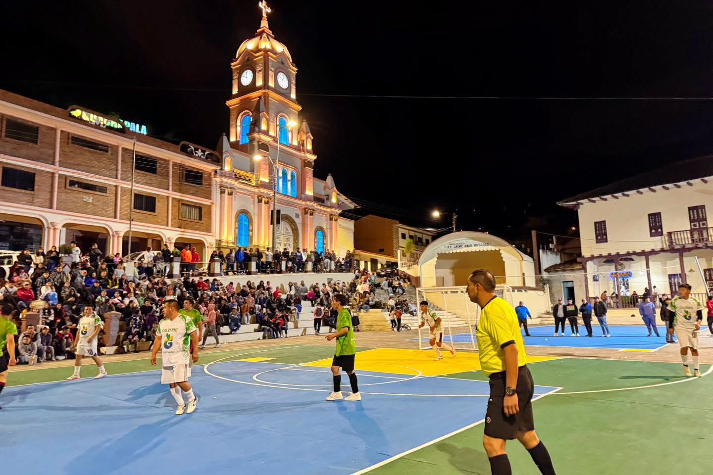 Encuentro deportivo de la gran final con jugadores, asistentes y la iglesia del cantón al fondo